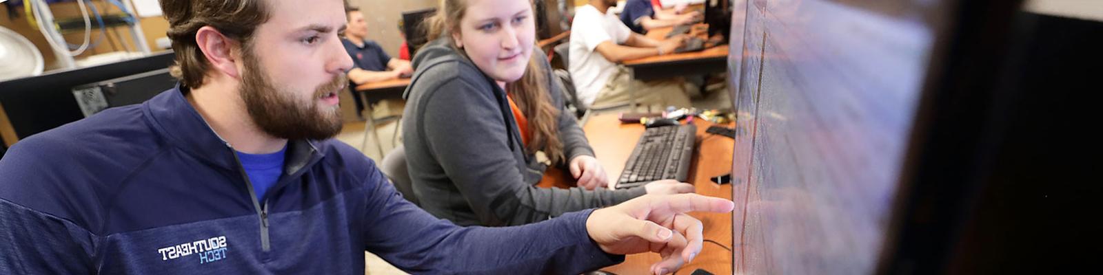 Two Southeast Tech students in a classroom, collaborating in front of a desktop computer